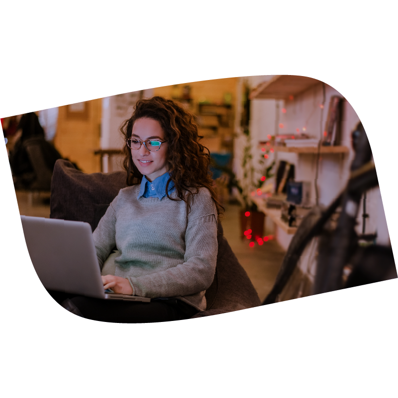 Seated woman smiles an types on laptop