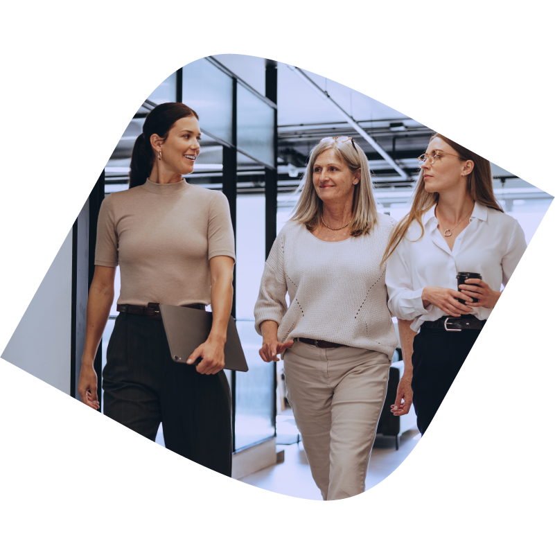 Three women walk down hallway talking to each other