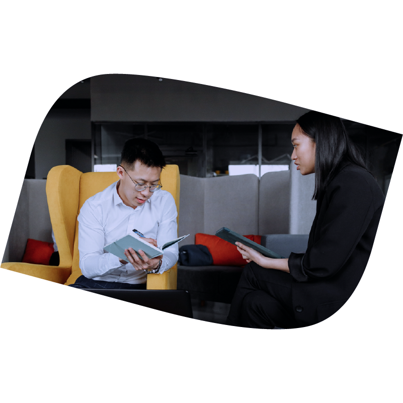 Man writes in a notebook and woman holds a table while talking to him